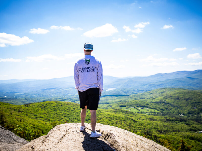 student on a mountain looking out into the valley