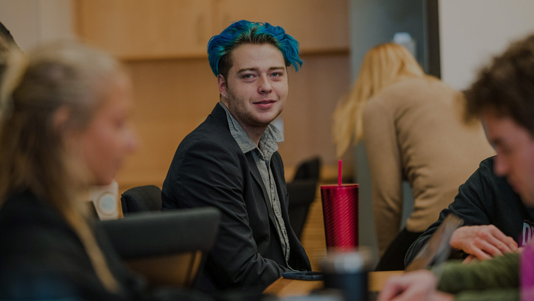 student with blue hair looks at camera