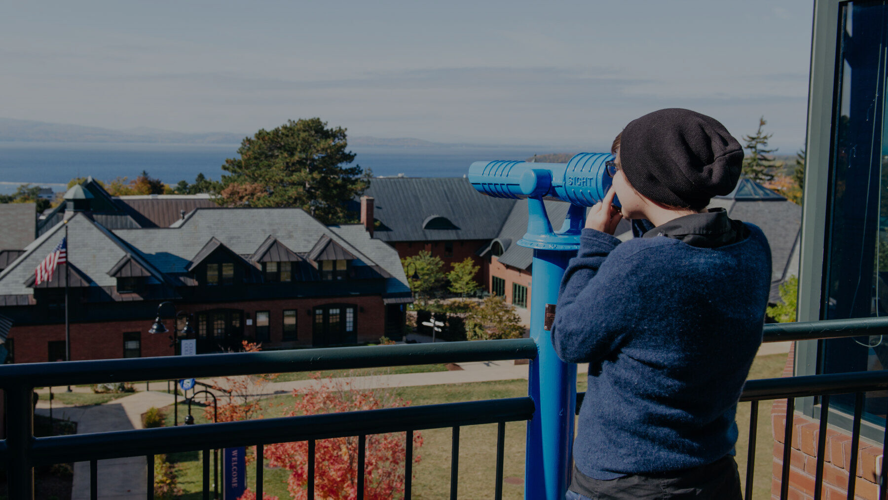 student looking out towards Lake Champlain through a telescope